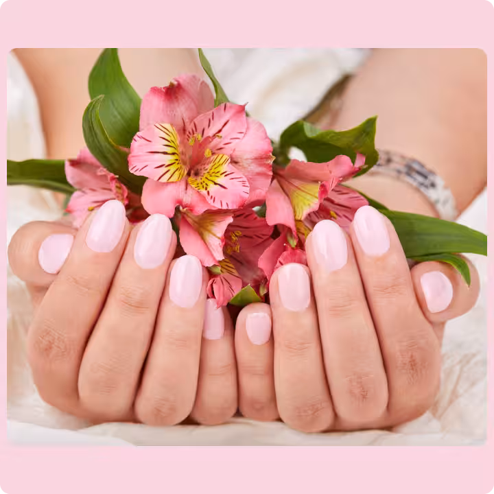 A woman's hands with soft pink nail polish gently holding a bouquet of flowers