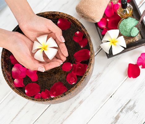 Woman's hands in a spa bowl with floating flowers